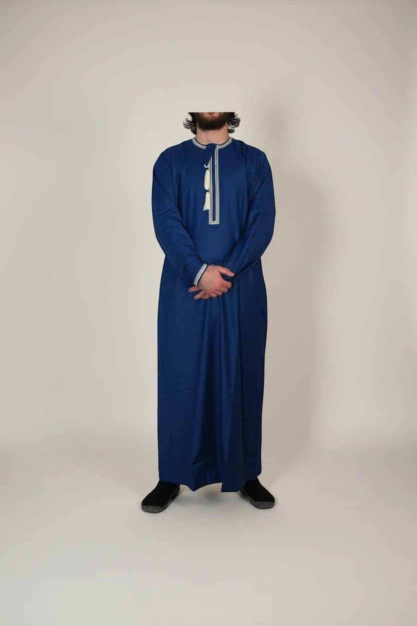 Khayr Thobes deep blue traditional thobe with white embroidery and tassel detail on neckline and cuffs.