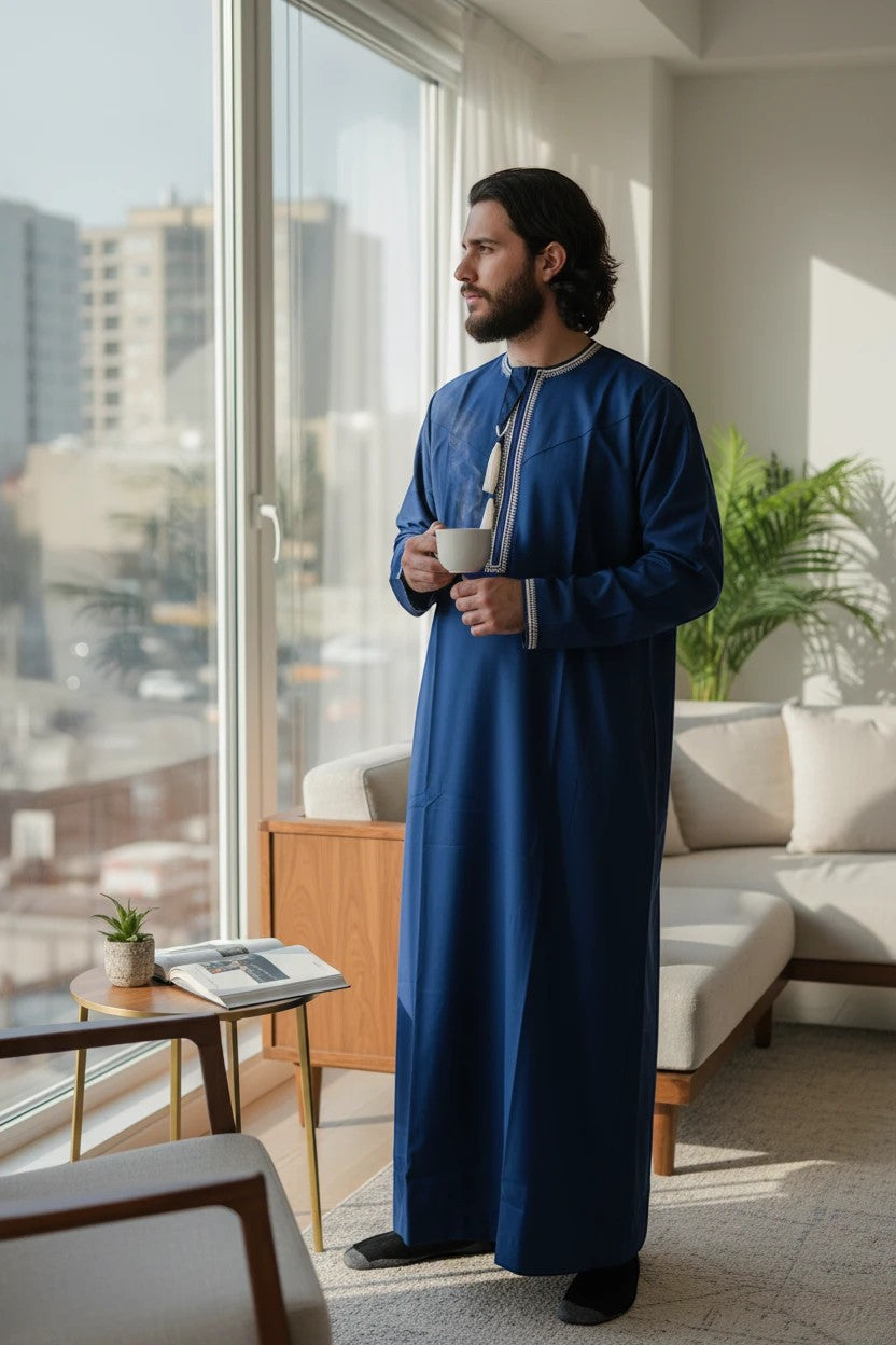 Khayr Thobes deep blue traditional thobe with white embroidery and tassel detail. Men's long sleeve garment.