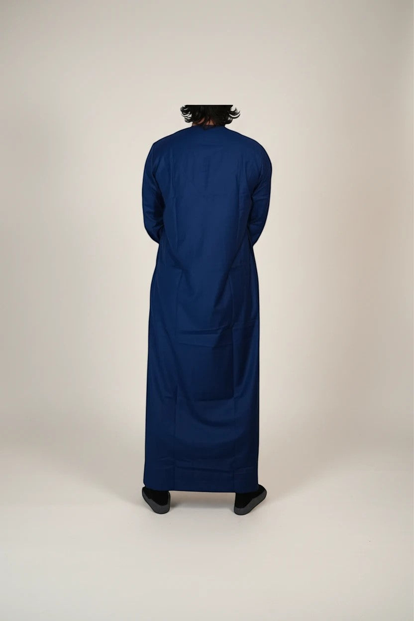 Khayr Thobes deep blue traditional thobe with tassel detail and white embroidery on neckline and cuffs.